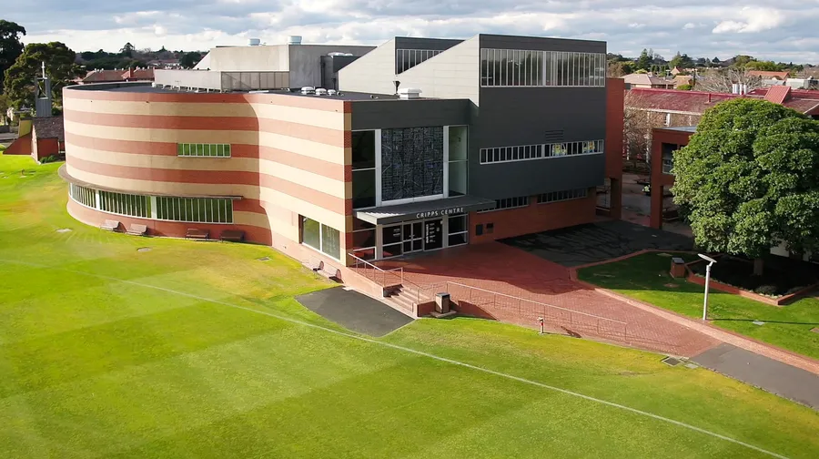 A modern university campus building with glass windows and green lawns